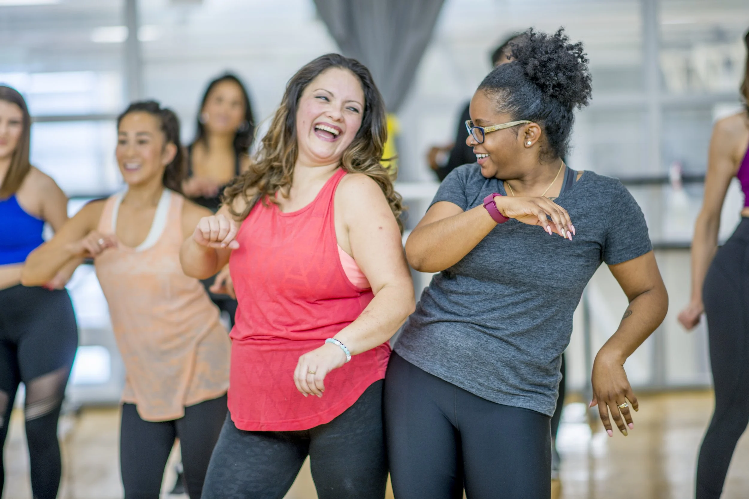 Two Dance Jam students laughing as they bump hips together mid-class at the Artaluma studio