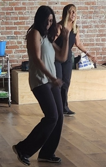 Two Artaluma students laughing mid-step during a Dance Jam class in the studio