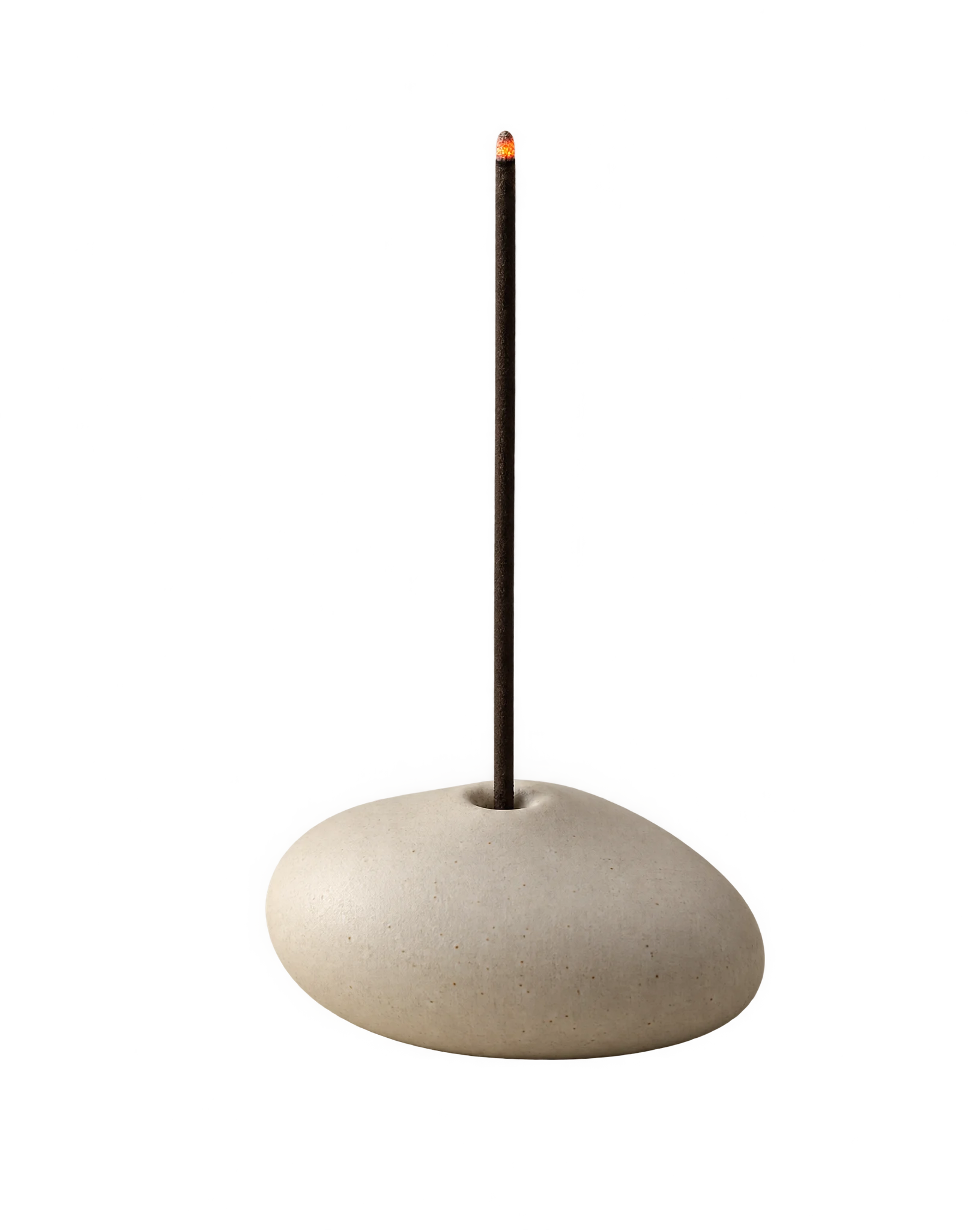 An ivory ceramic pebble incense holder with one lit stick