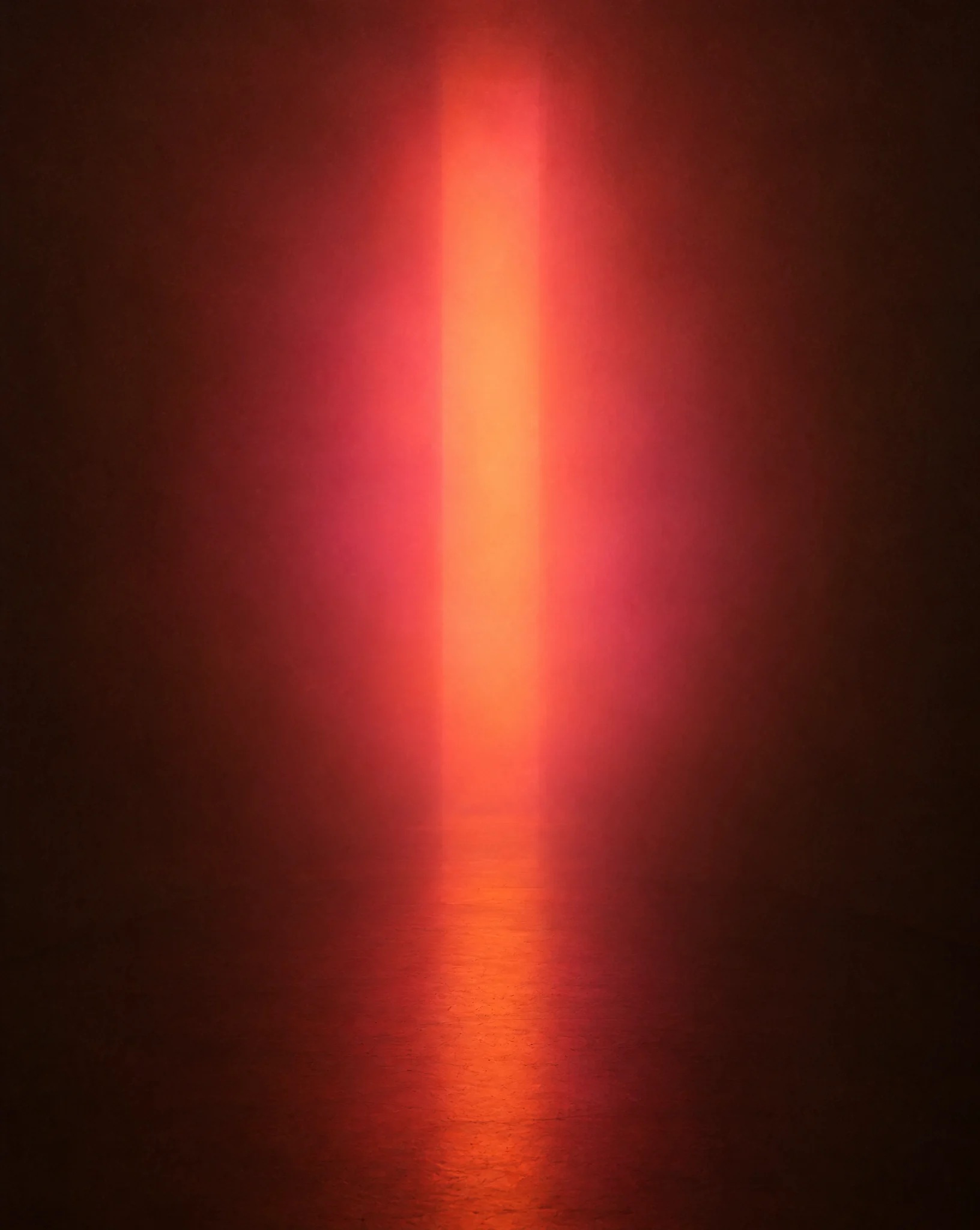 A single tall column of coral and apricot light glowing in a dark, hazy room