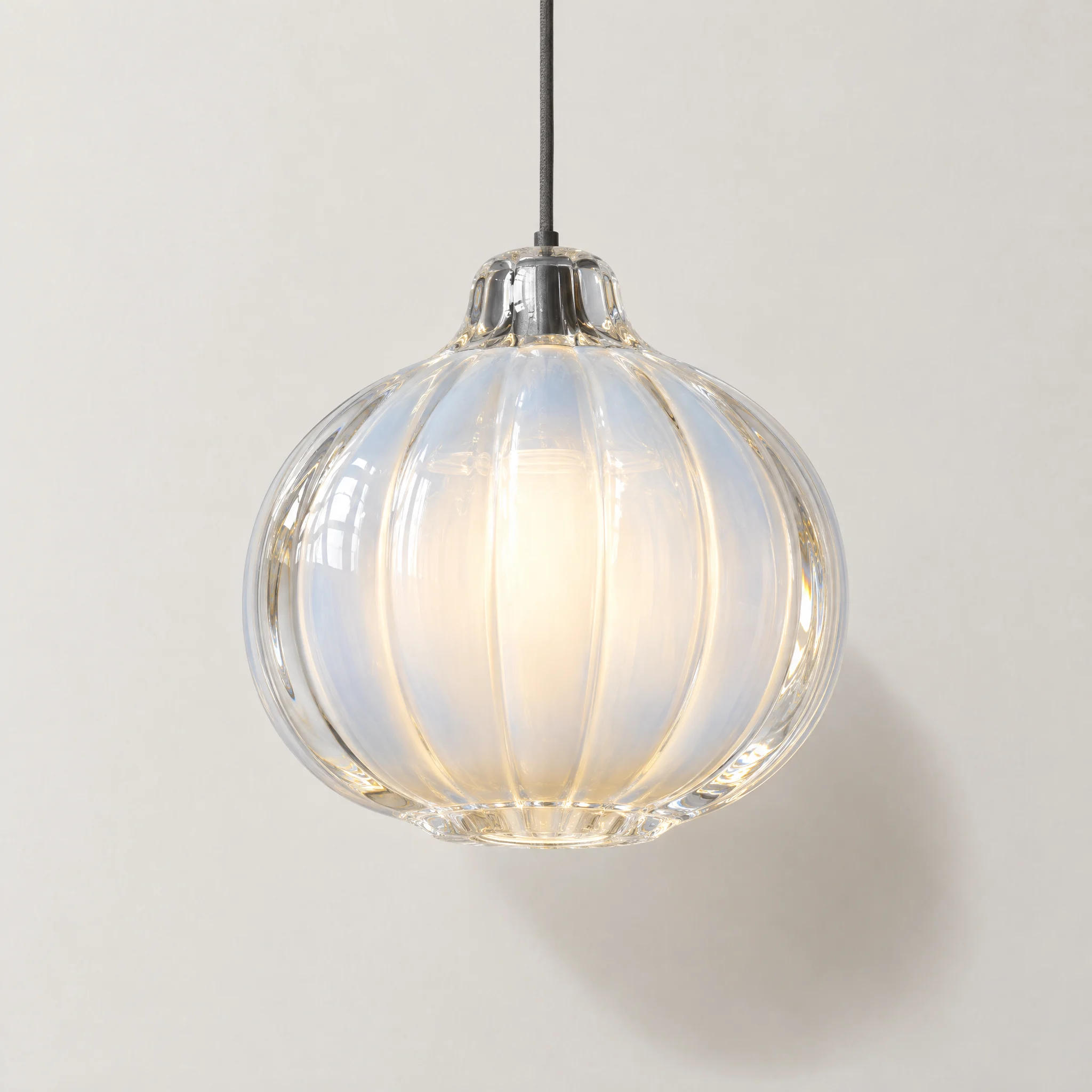 A ribbed opal glass pendant lamp glowing softly against a pale wall