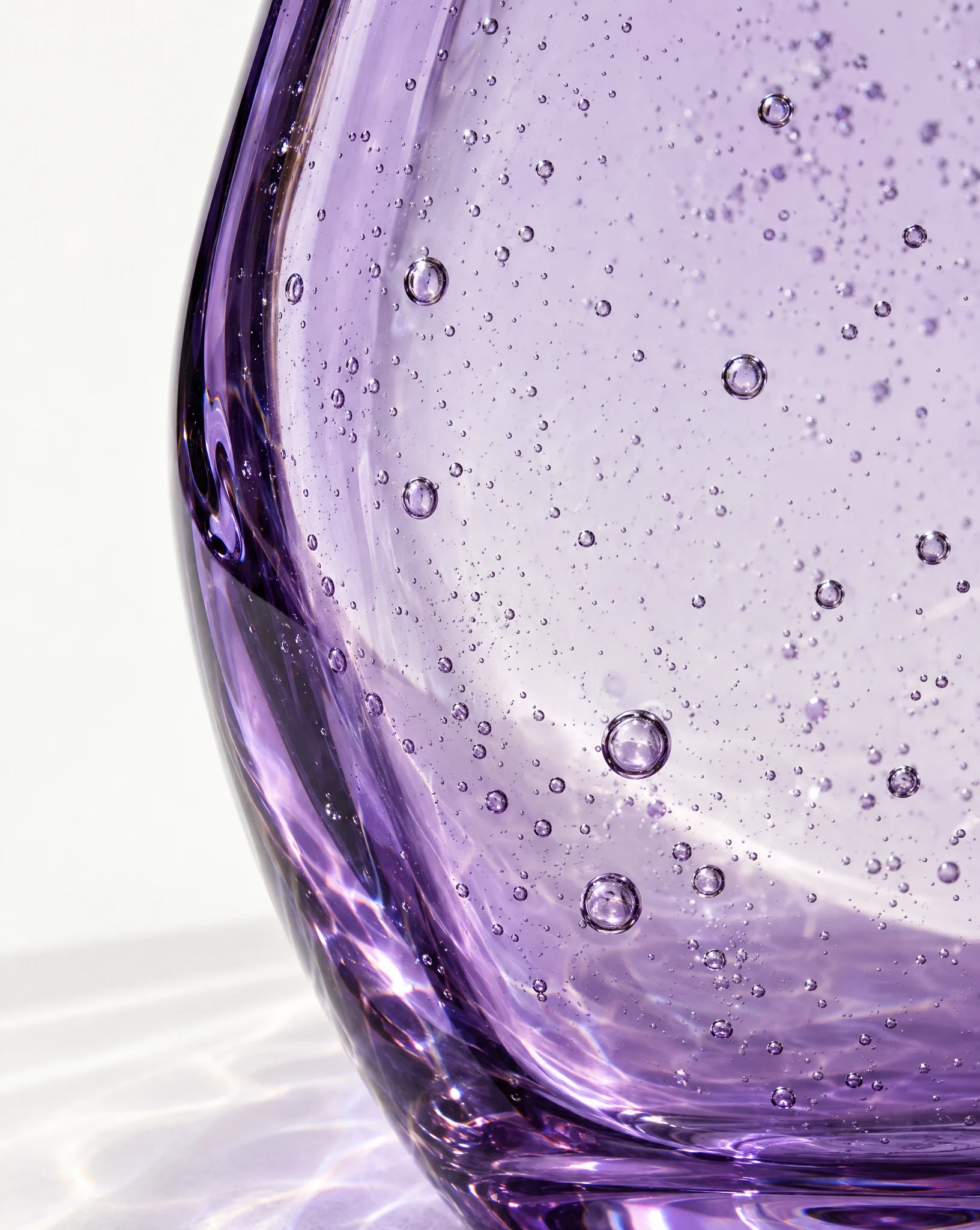 Close view of violet glass with small air bubbles caught inside the wall