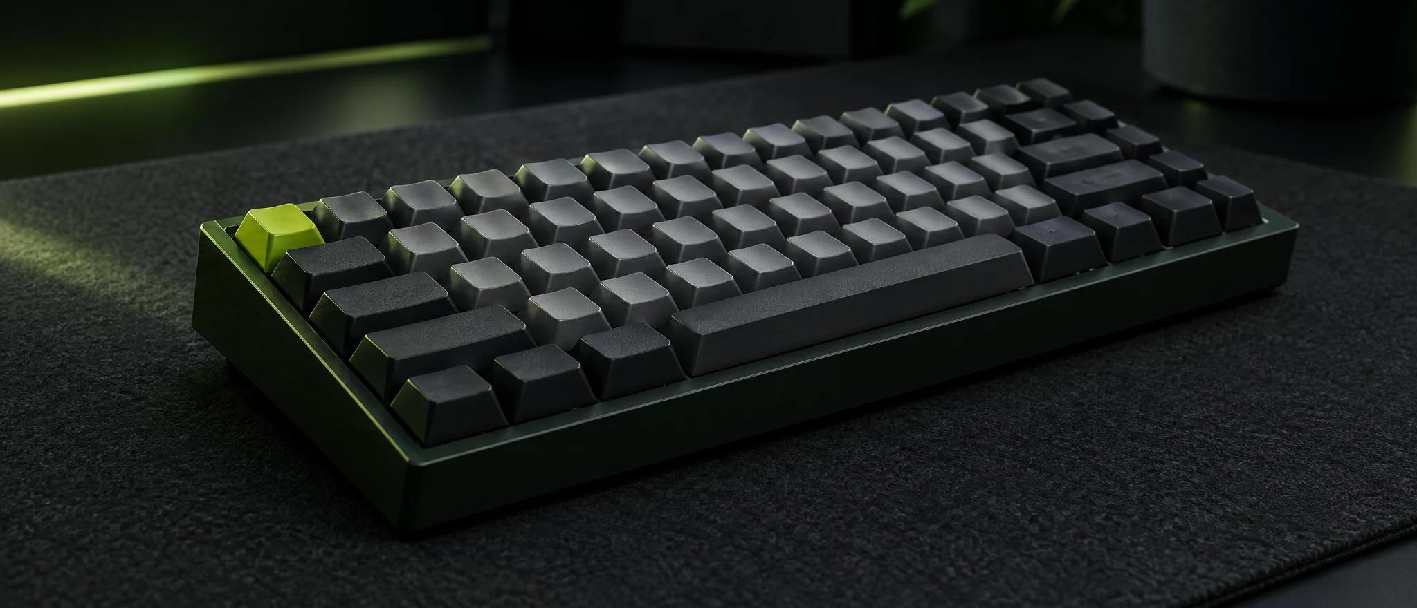 A compact graphite mechanical keyboard with a single lime key, lit by a thin line of green light