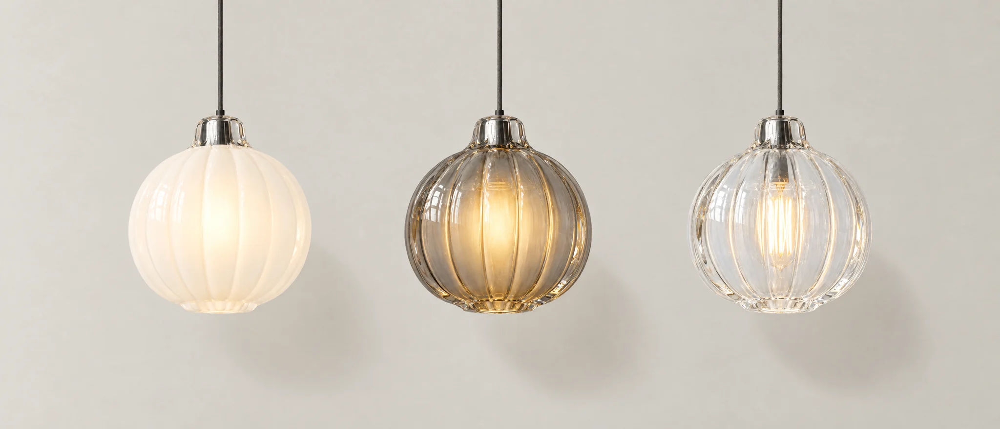 The same ribbed globe pendant in opal, smoke and clear glass, hanging side by side and lit