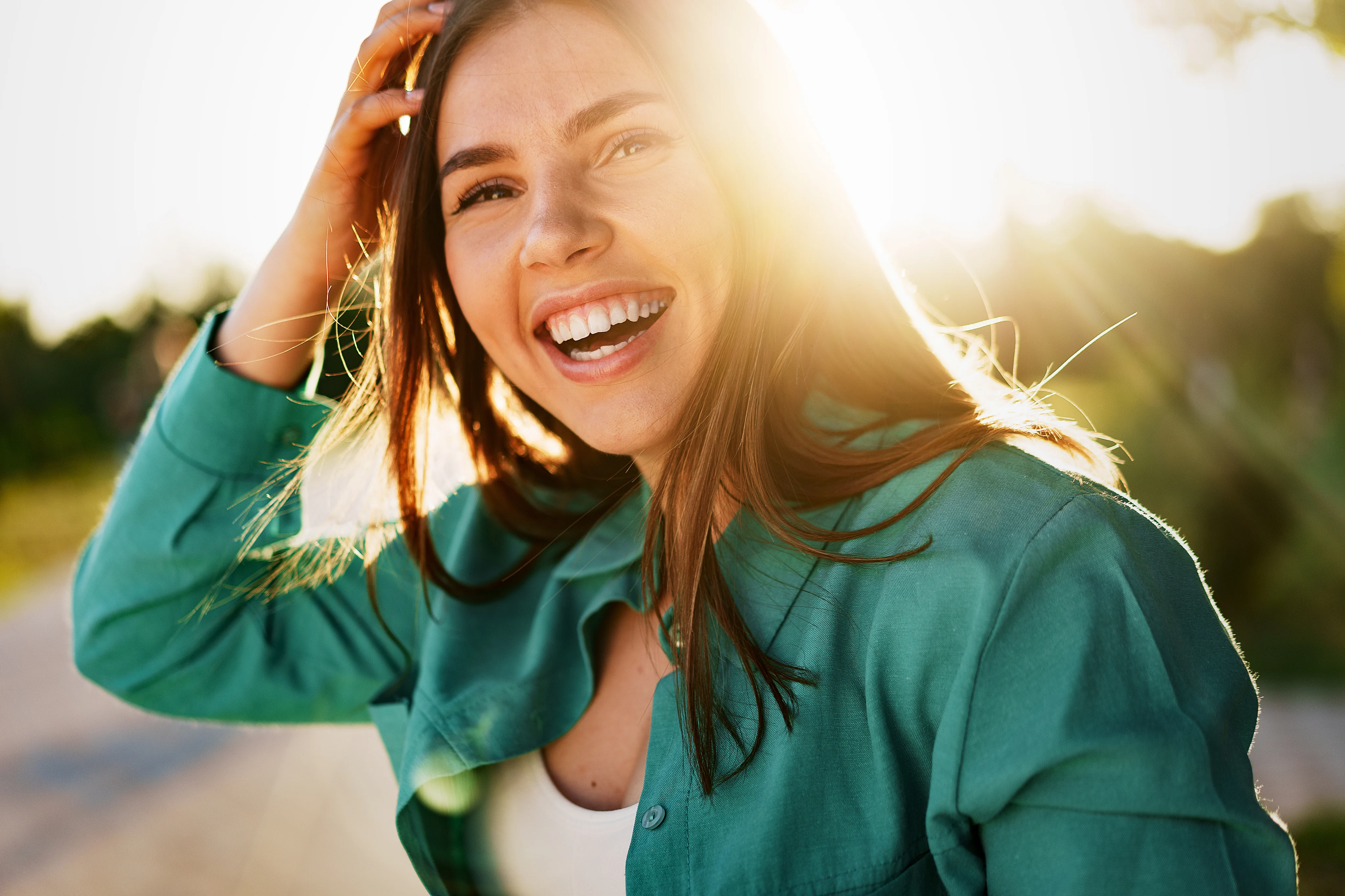 A woman smiling outdoors in warm sunlight