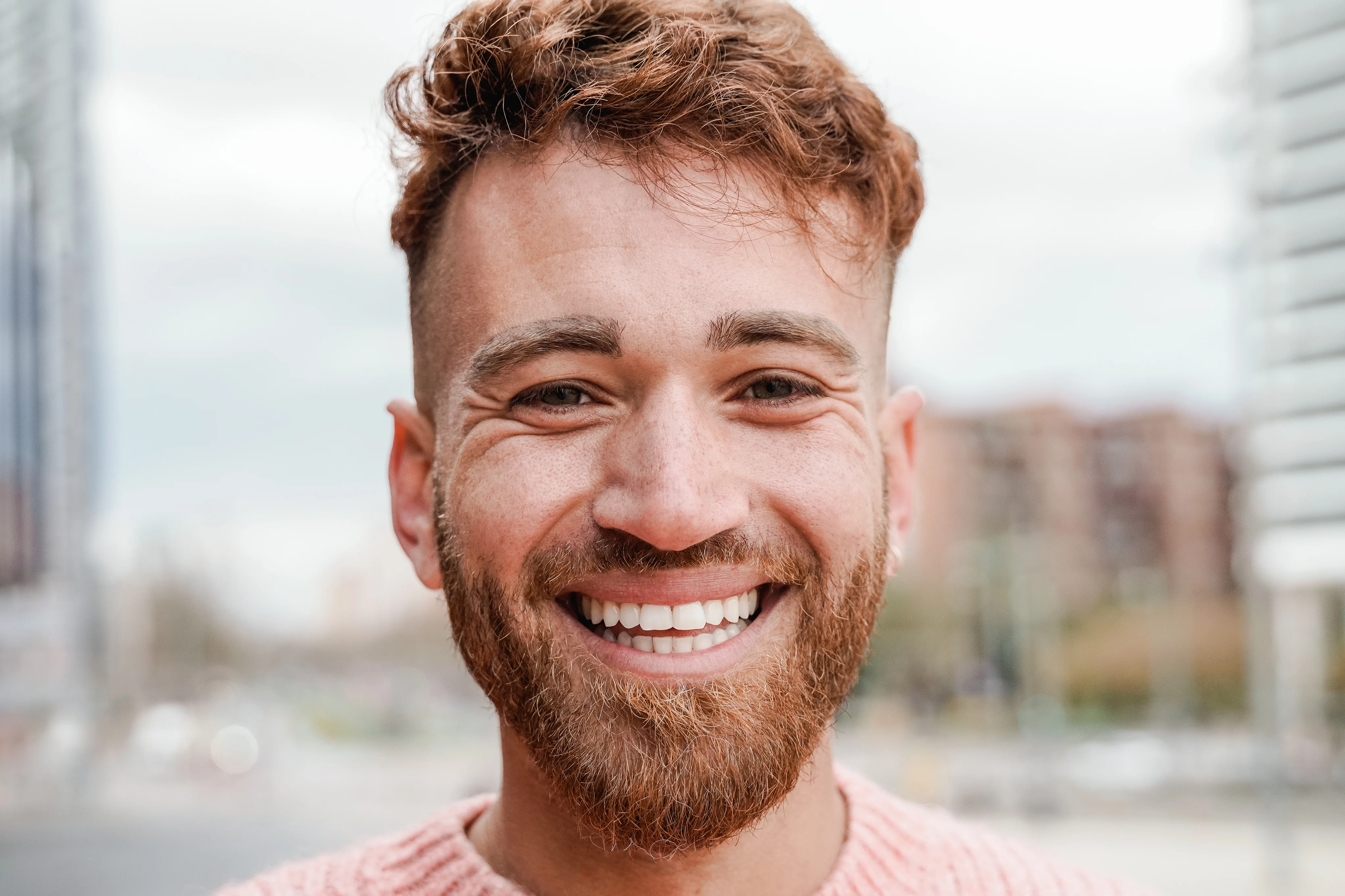 A smiling man with red hair outdoors