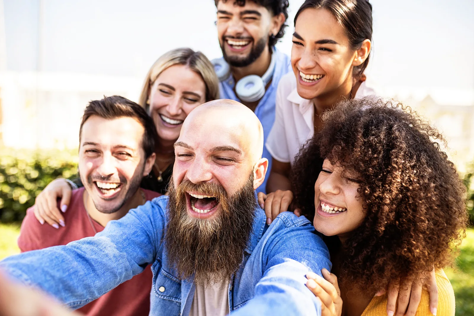A group of friends laughing while taking a selfie outdoors