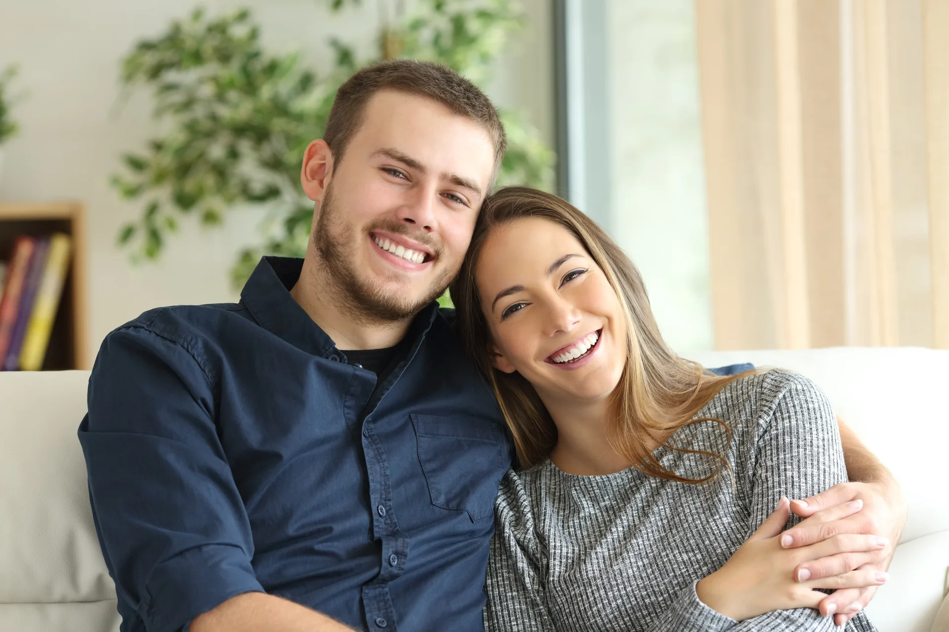 A smiling couple sitting close together on a sofa at home