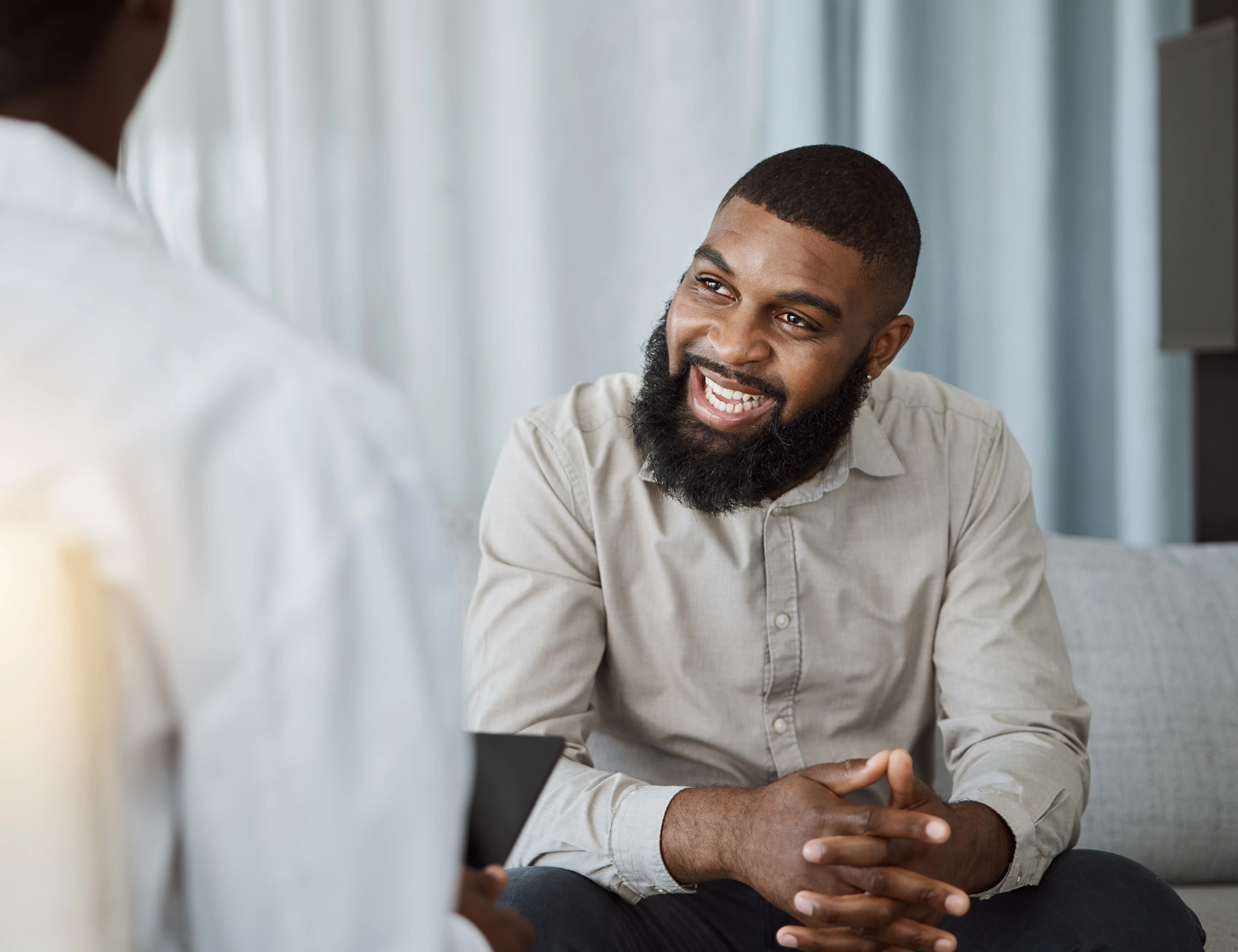 A smiling man speaking with someone seated across from him