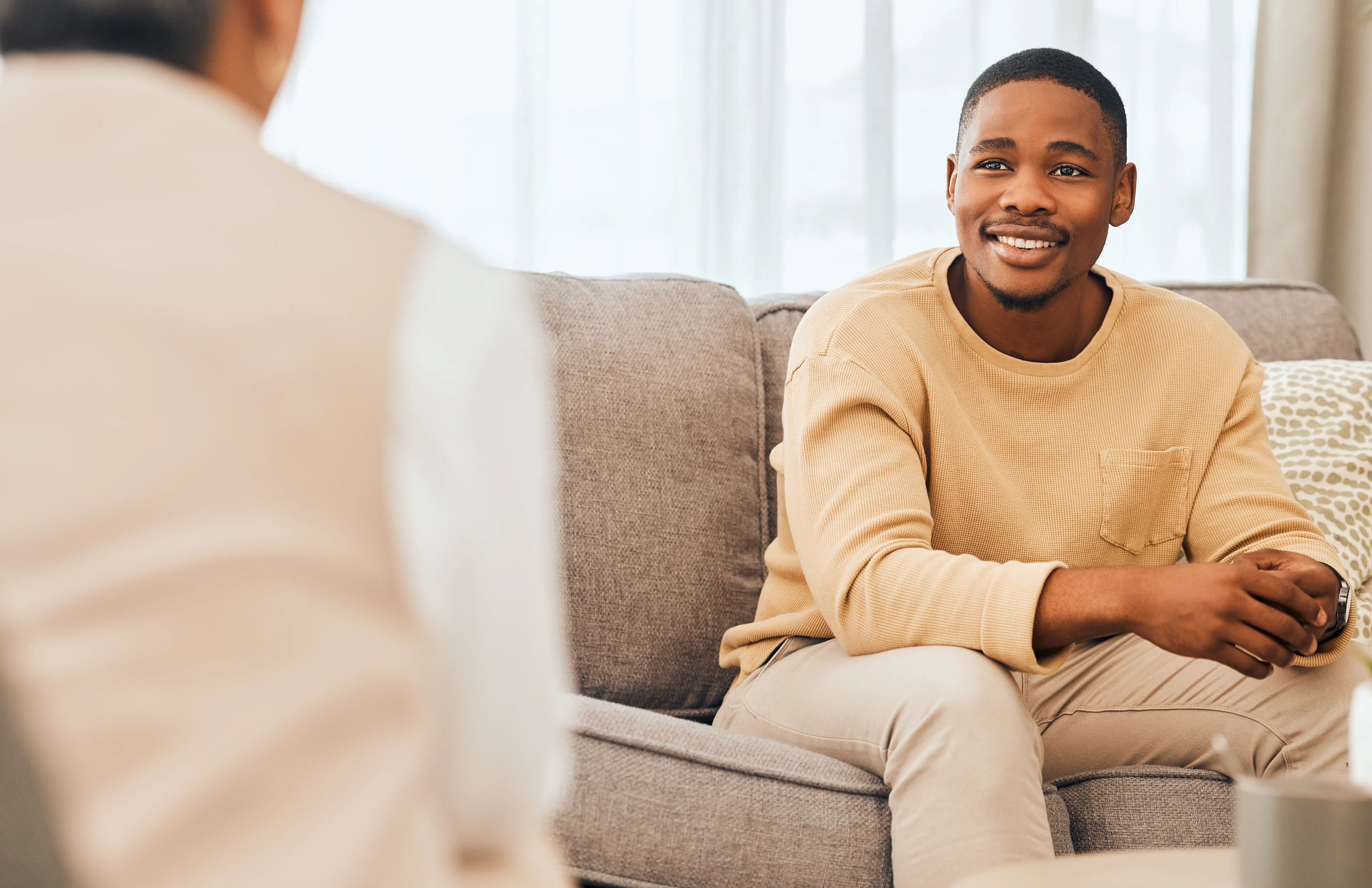 A man talking with another person while seated on a sofa