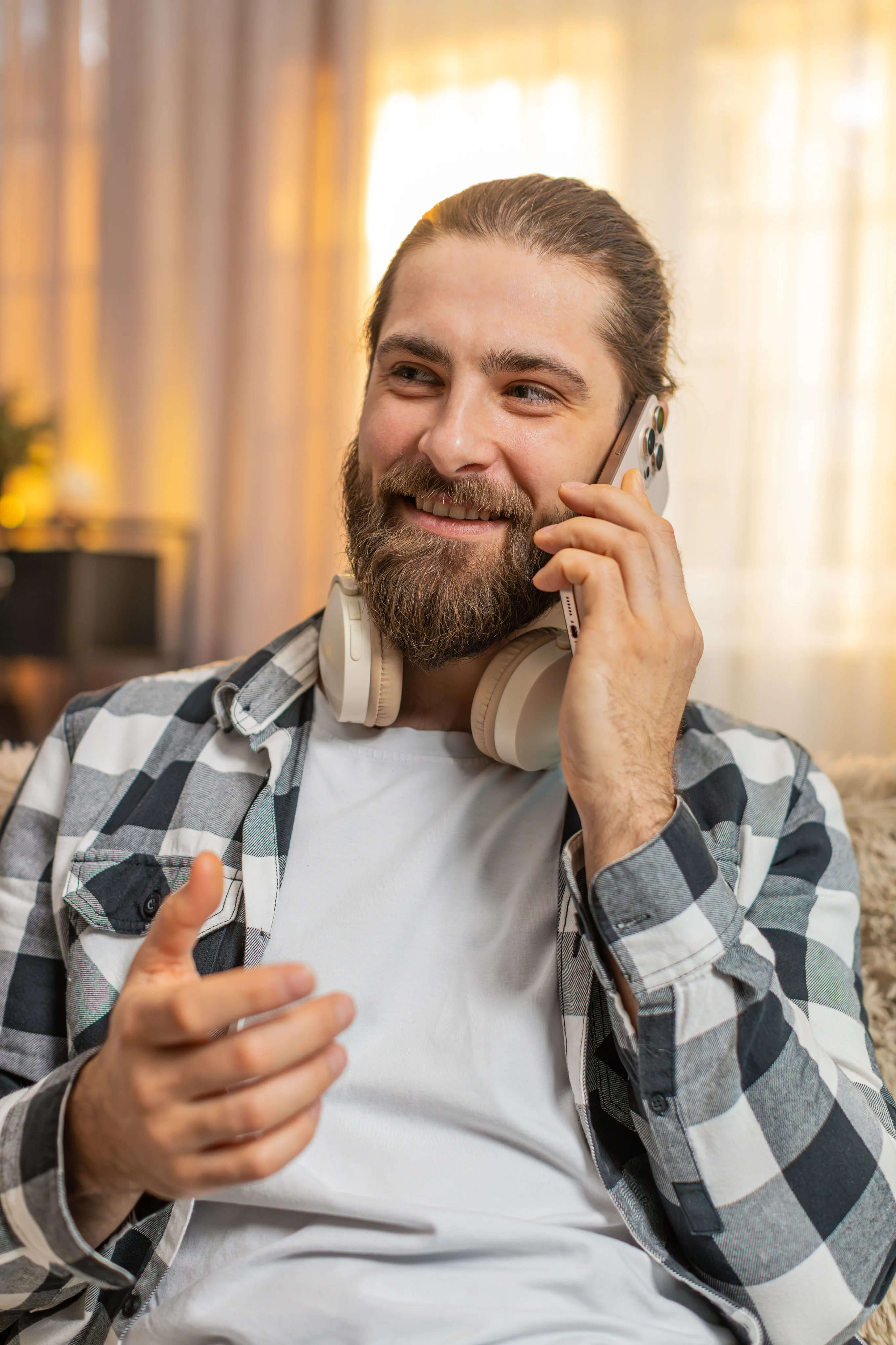A smiling man having a phone conversation with headphones around his neck