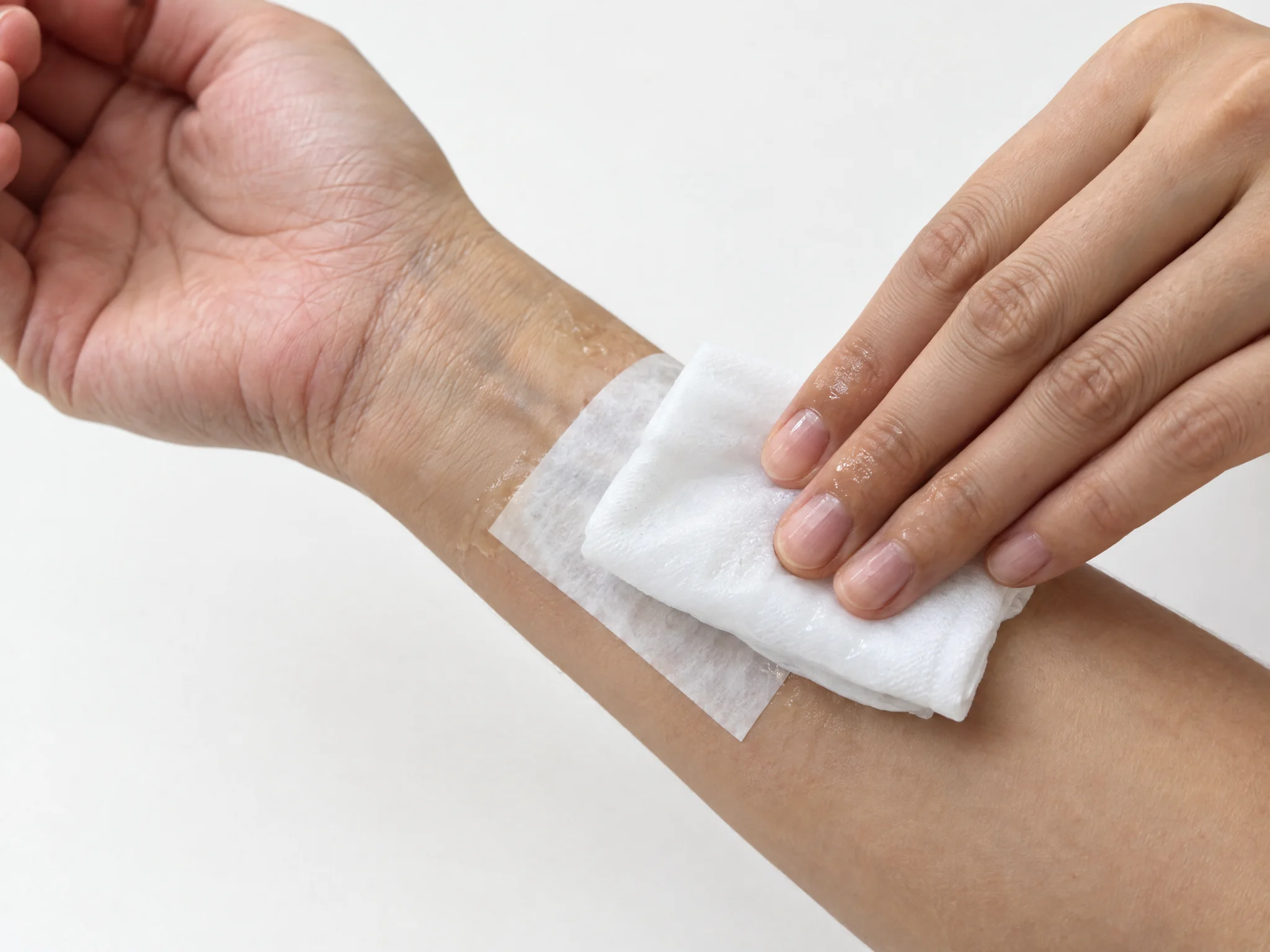 A damp white cloth pressed over a temporary tattoo paper on the inner wrist