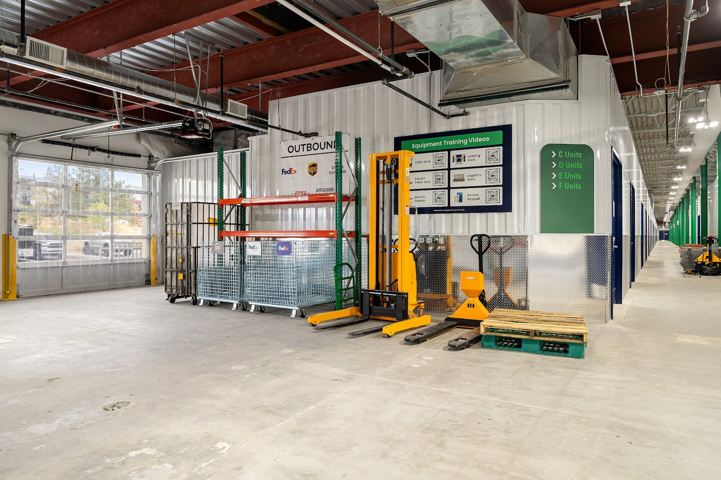 Shared WareSpace loading and equipment area with pallet jacks, an electric stacker, and carrier outbound bins