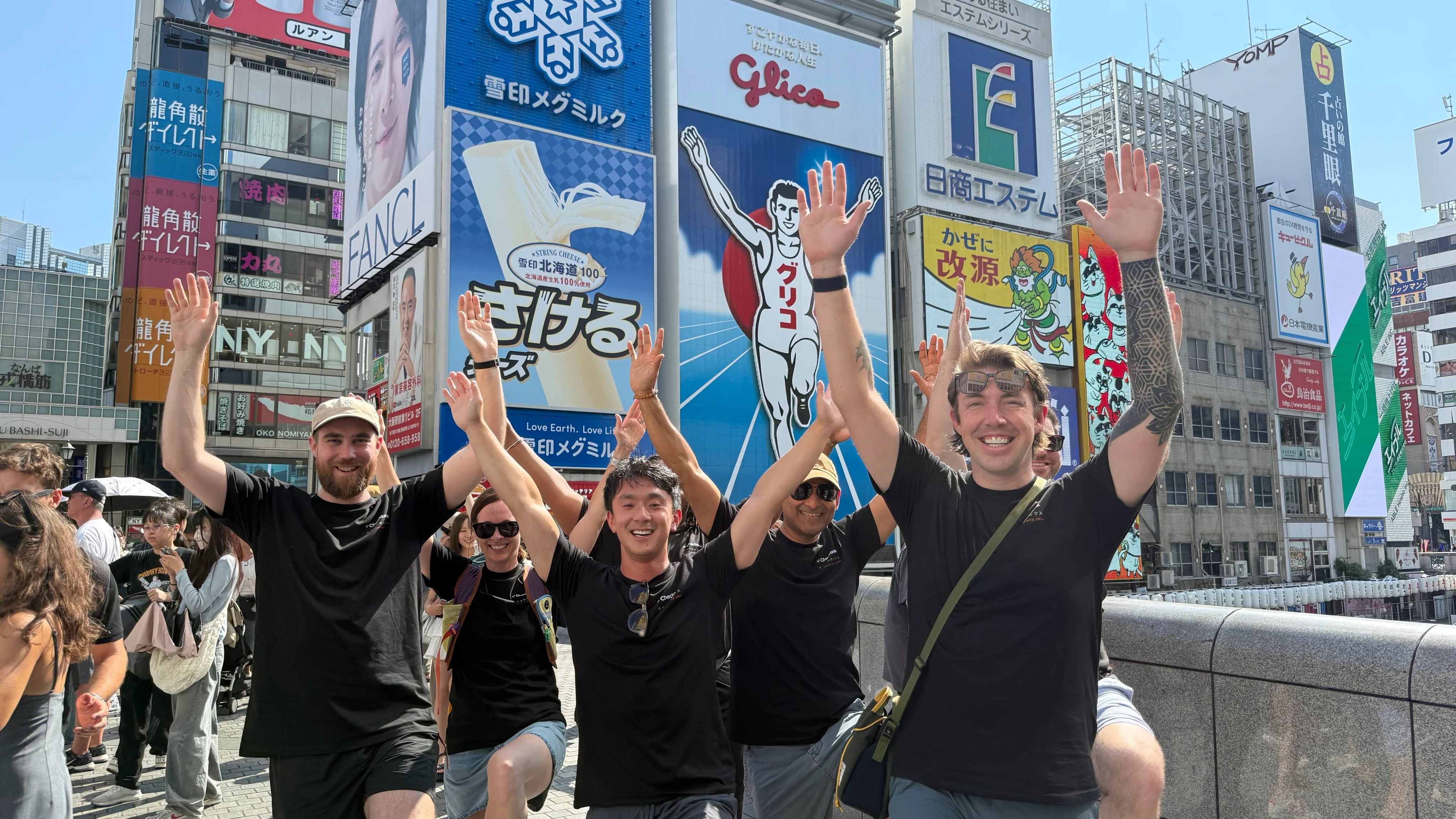 Checkbox teammates waving together on a city street in Osaka