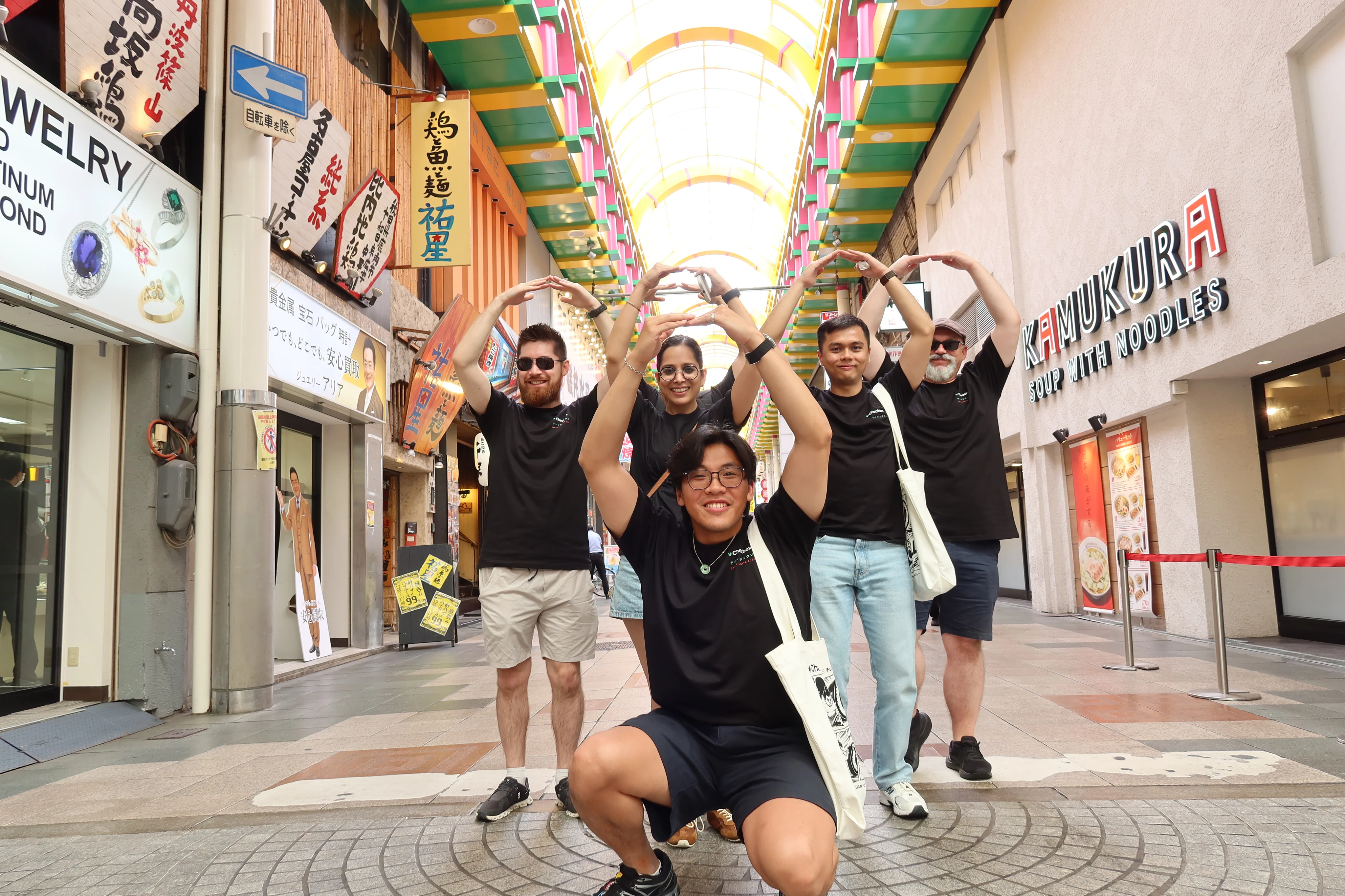 Checkbox teammates posing together in a Japanese shopping arcade
