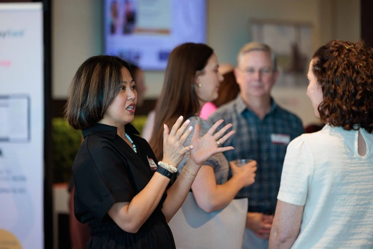 An attendee talks with her hands in a small group during networking at AI ❤️ CX Atlanta