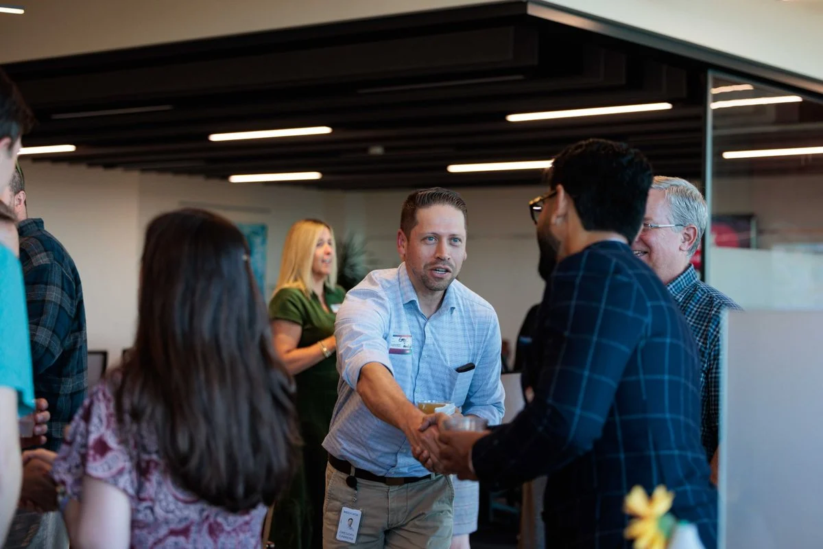 Two attendees shake hands while others talk nearby at AI ❤️ CX Atlanta
