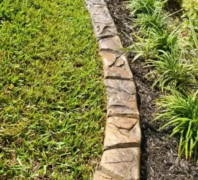 Natural stone stamped concrete curbing along a landscape bed