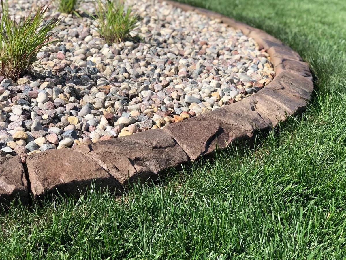Brown stone-textured decorative concrete curbing around a rock-filled garden bed