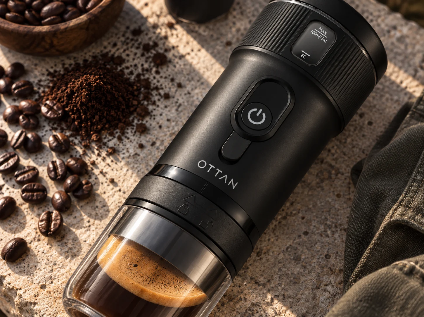 Diagonal close-up of OTTAN Nord highlighting its display, power control, wordmark, locking ring and brewed espresso
