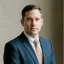A confident man in a sharp blue suit and peach tie, representing PointOne's expertise in digital product solutions.