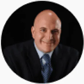 Louis Bevilacqua, a bald man in a dark suit and patterned tie, smiles confidently against a black background representing.