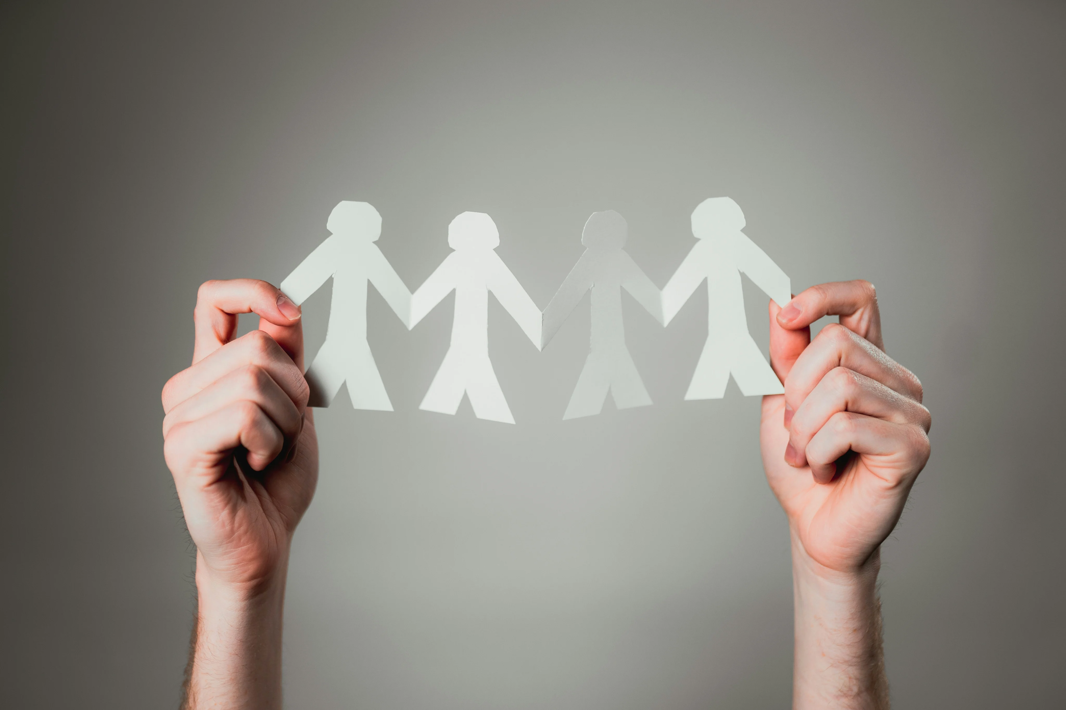 Hands holding a connected chain of paper people