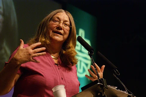 Elaine Storkey speaking at a conference lectern, gesturing as she talks