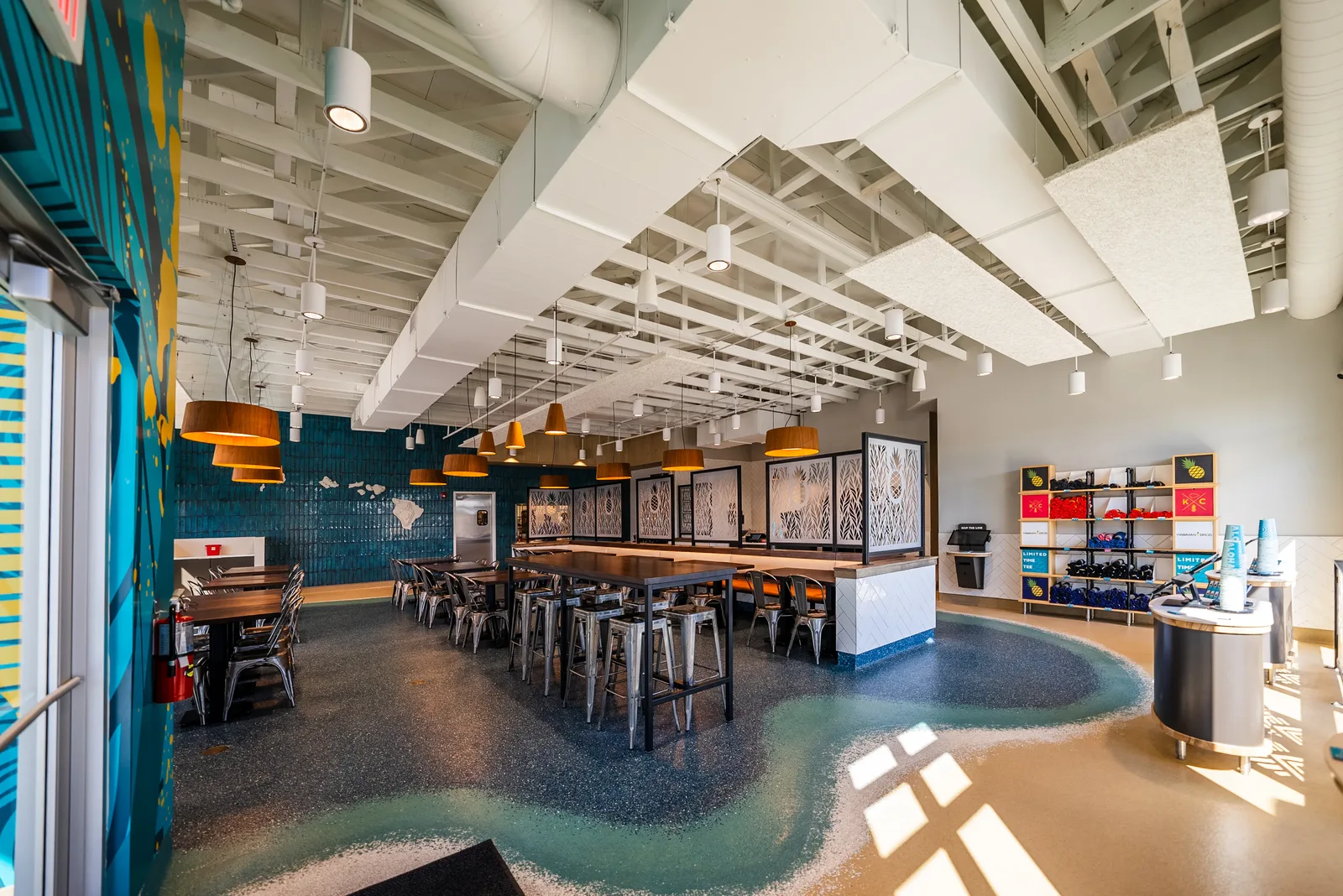 Hawaiian Bros restaurant interior with seating, custom partitions, lighting, and retail displays