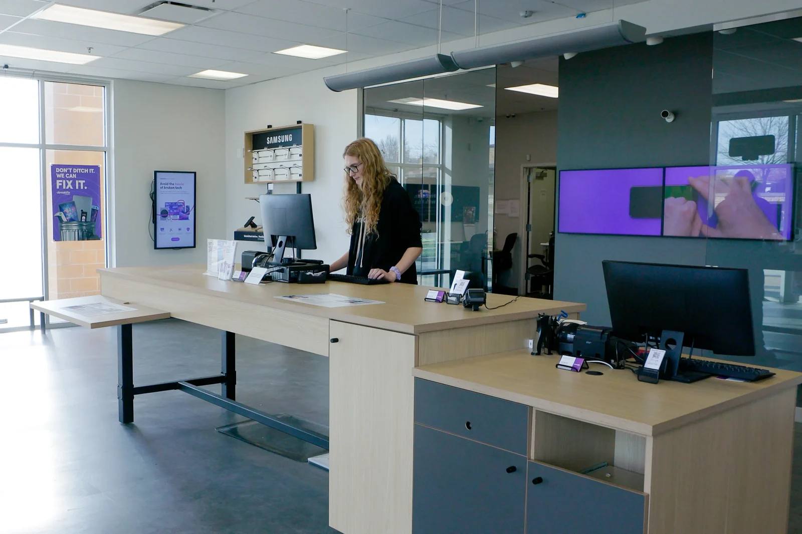 uBreakiFix service counter with an employee, retail displays and digital signage.