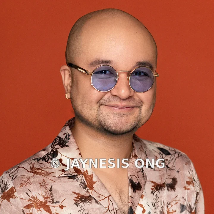Portrait of Jaynesis Ong wearing round glasses and a patterned shirt
