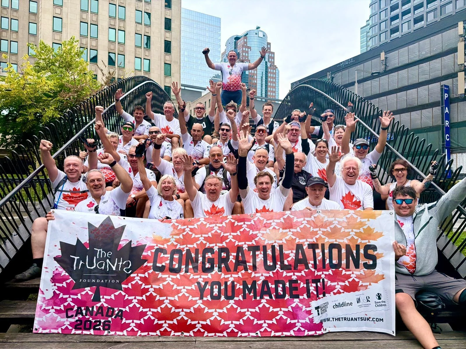 Truants Foundation Canada 2026 riders celebrating together in Montreal behind a congratulations banner