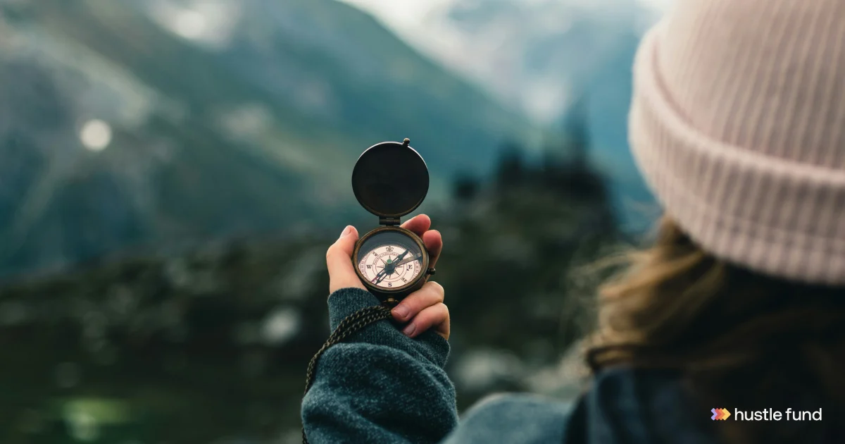 A person holding a compass while looking toward distant mountains