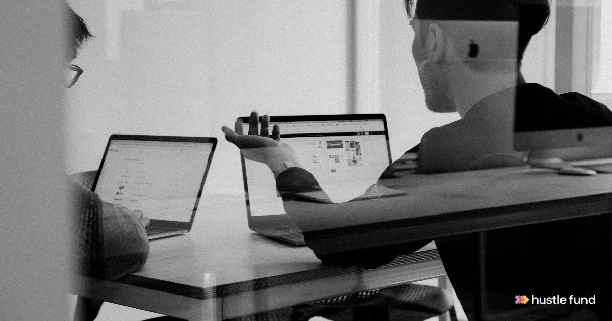 Founders talking around a table with laptops during an investor meeting