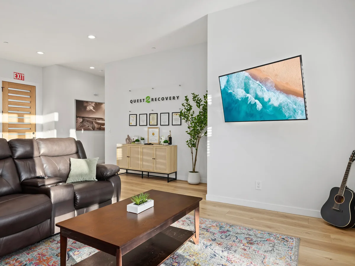 Quest 2 Recovery living room with leather seating, a television and a guitar