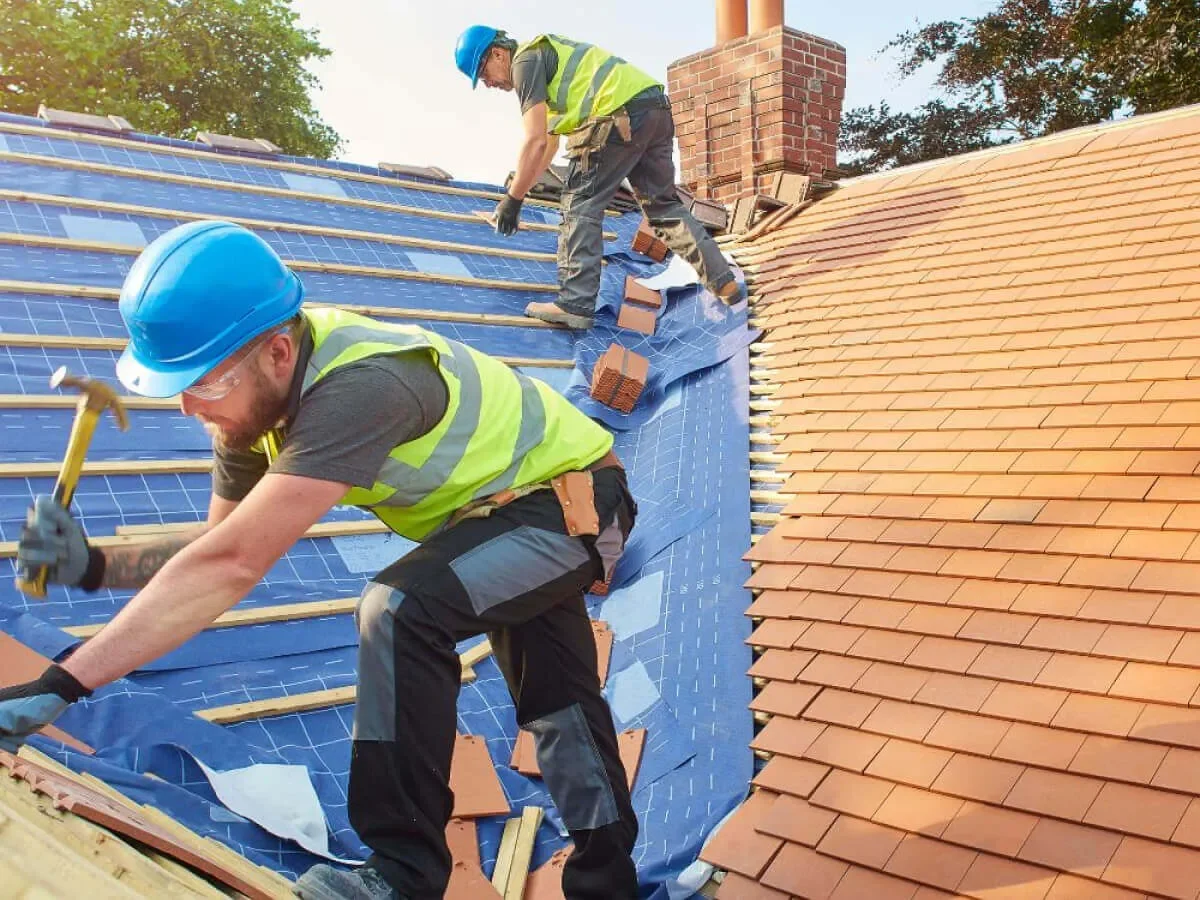 Two roof installers on a construction site installing a new roof for BauBau