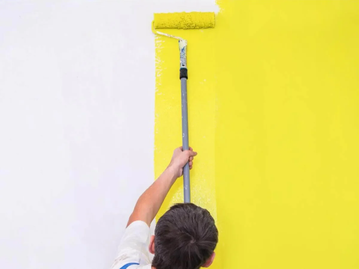 Maler streicht eine gelbe Wand