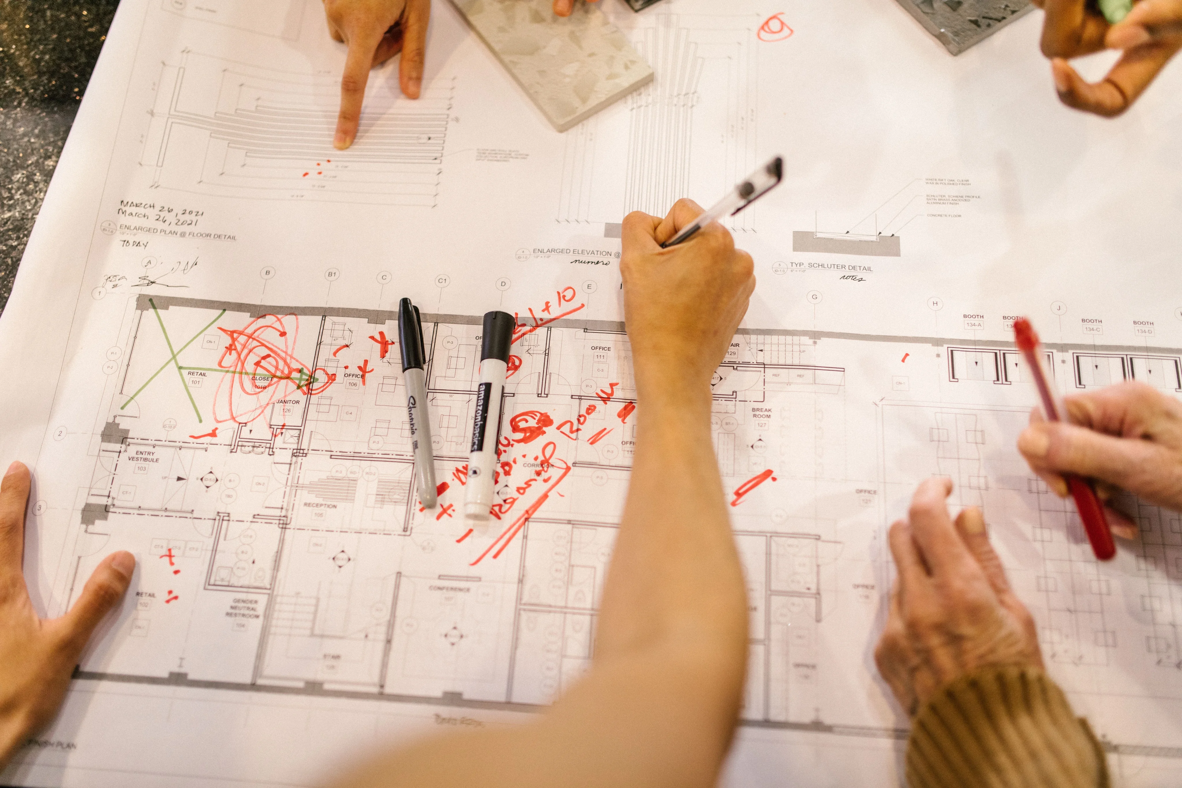 Illustrative overhead view of people marking up architectural plans