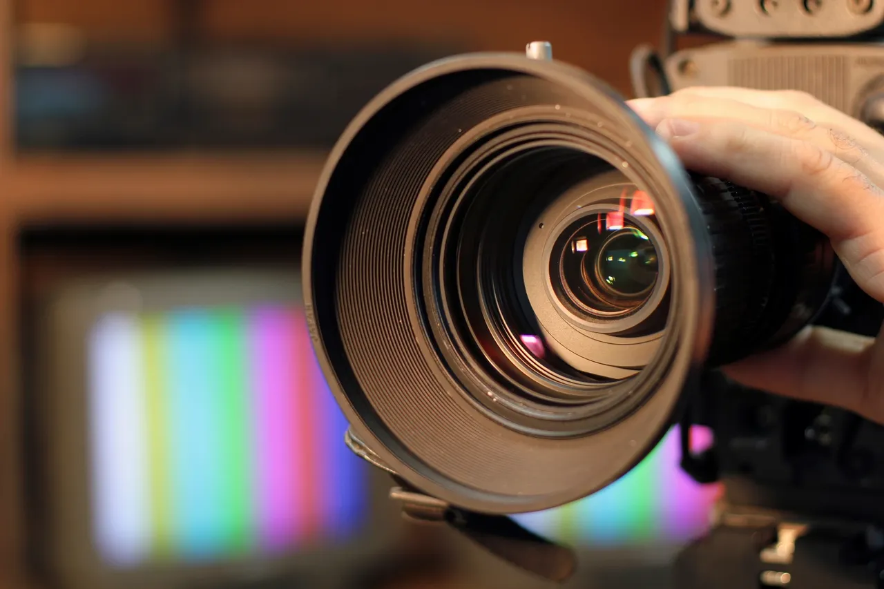 Close-up of a professional video camera lens with broadcast color bars in the background