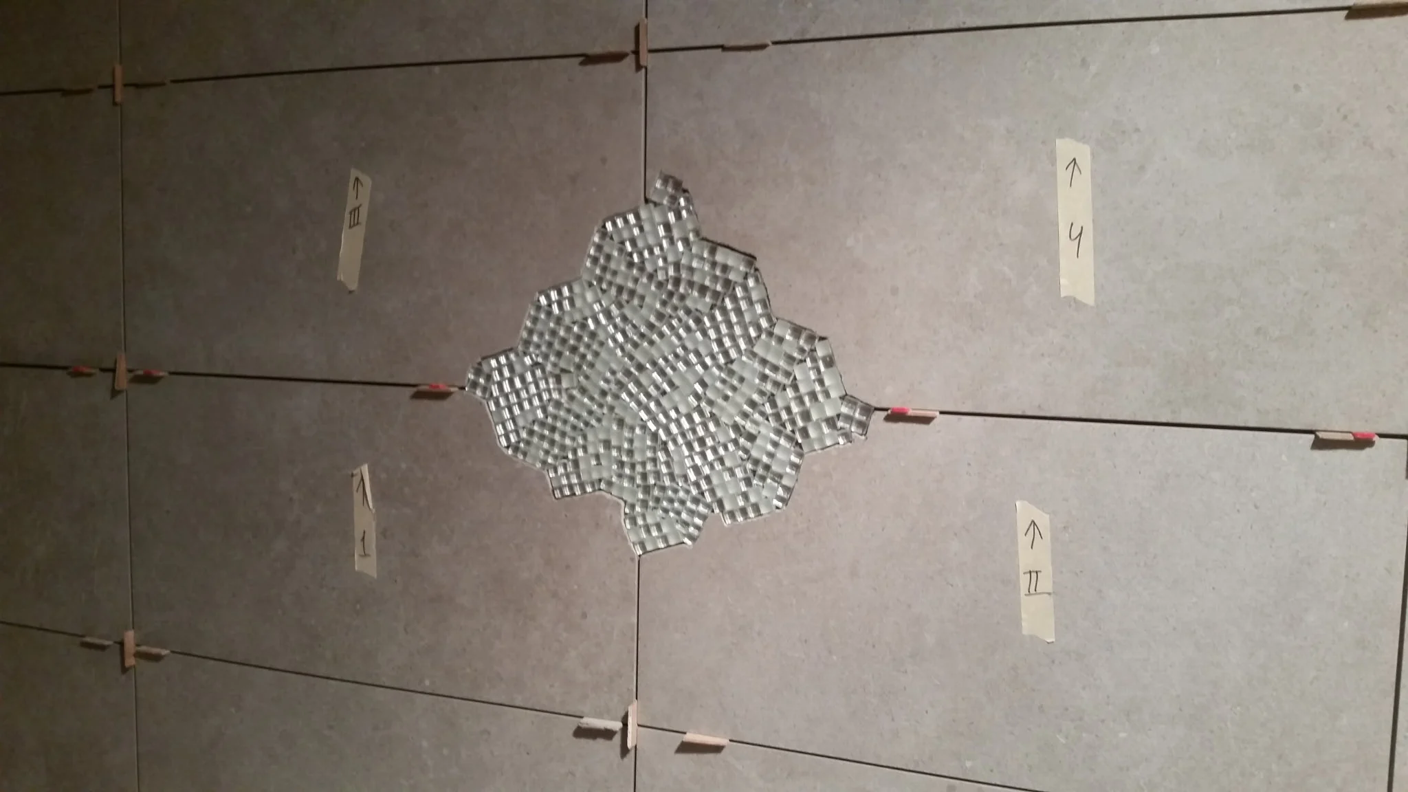 Large format tile laid out around a glass mosaic inlay with spacers and layout tape