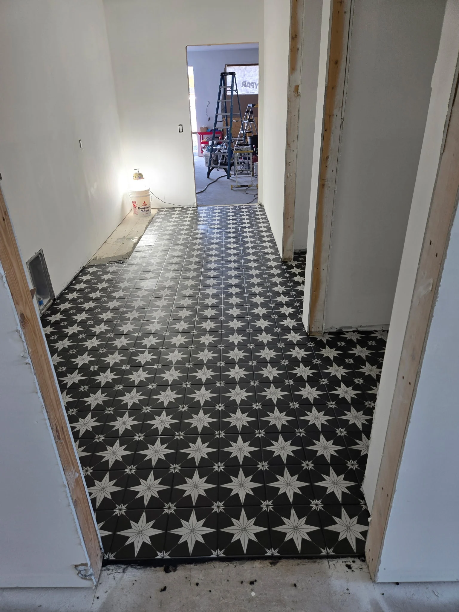 Black and white star pattern tile floor being installed down a hallway