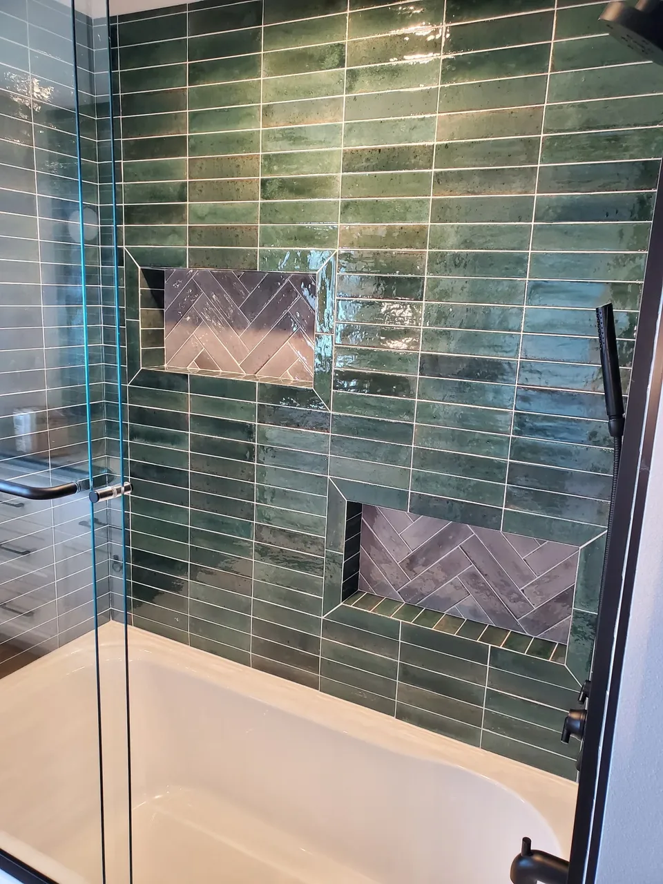 Tub and shower surround in green glazed tile with two herringbone niches