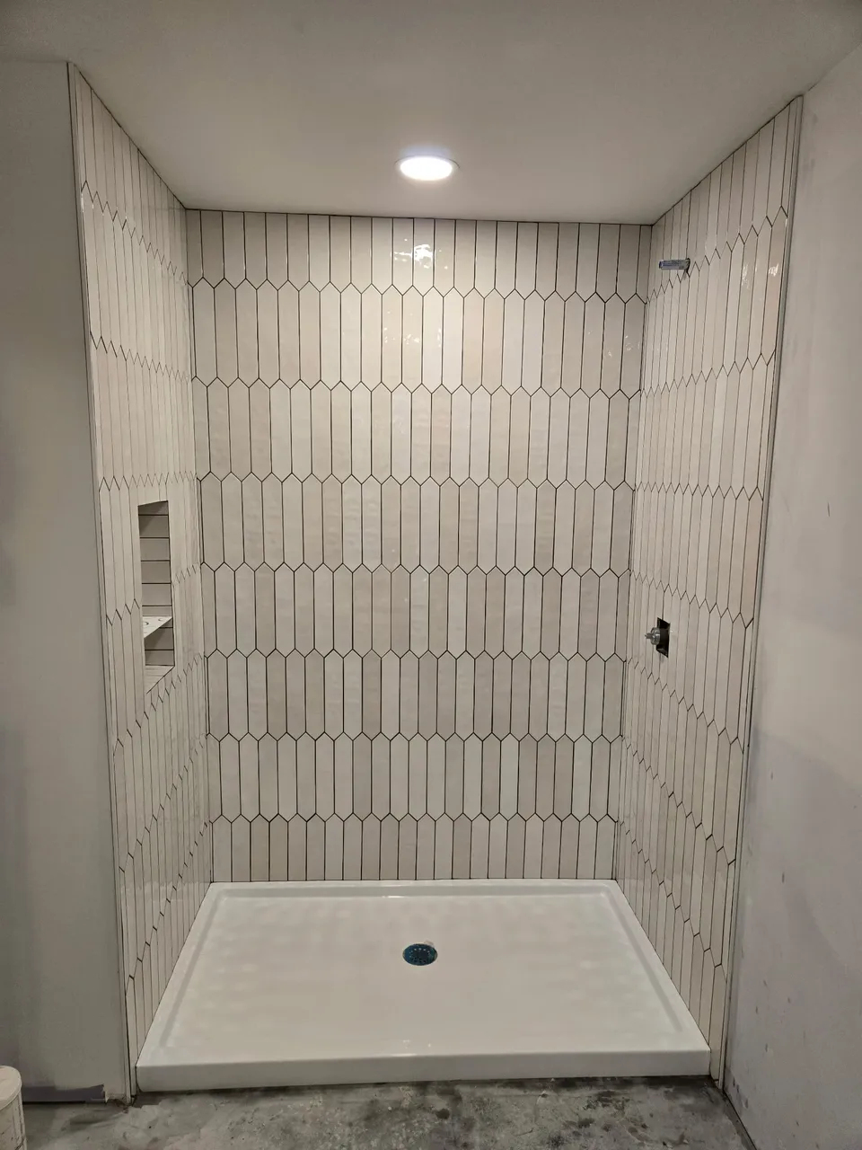 Shower surround in glossy white picket tile with a tiled niche