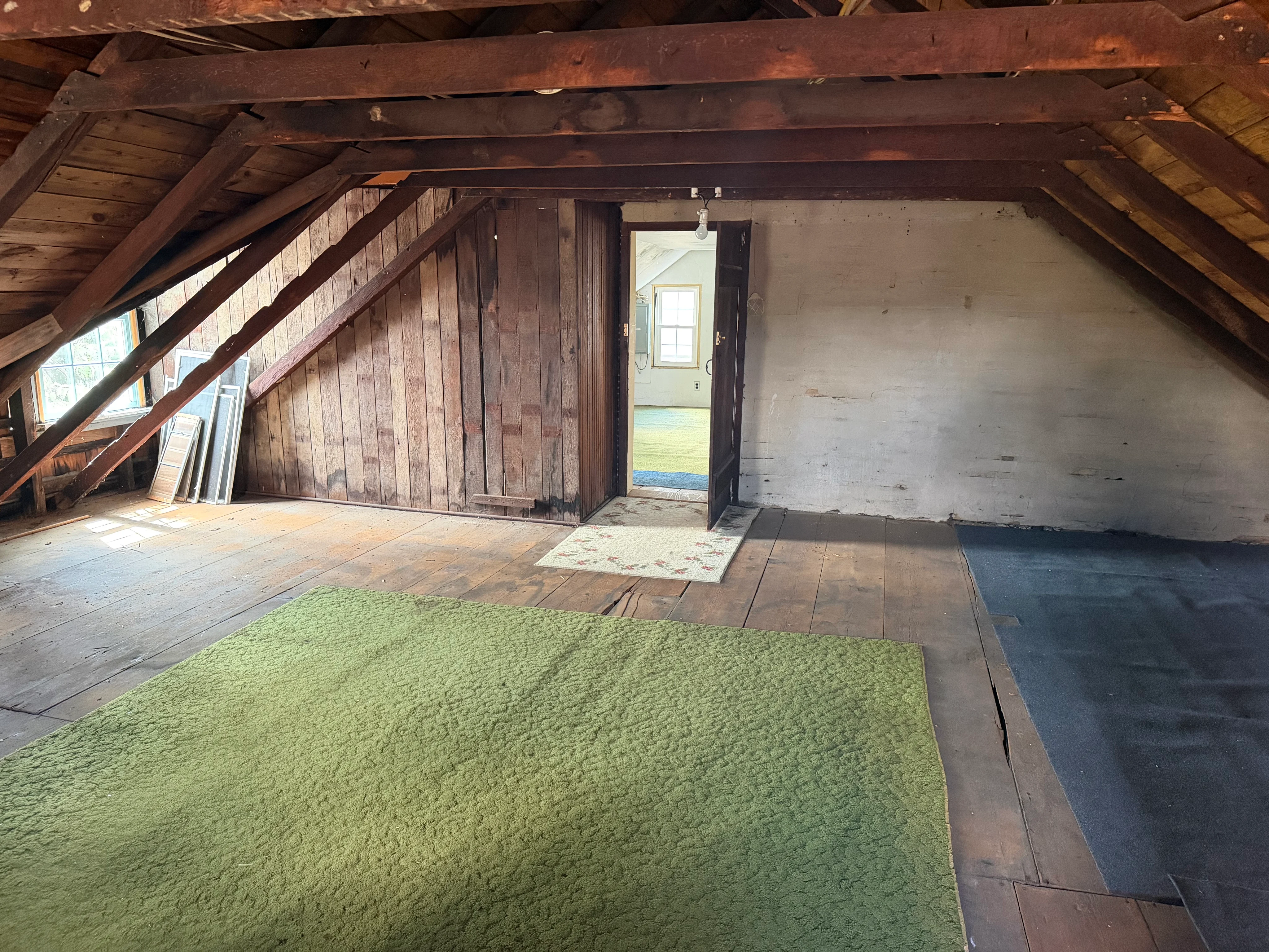 Existing unfinished third-floor attic with exposed rafters, plank floors, and original chimney
