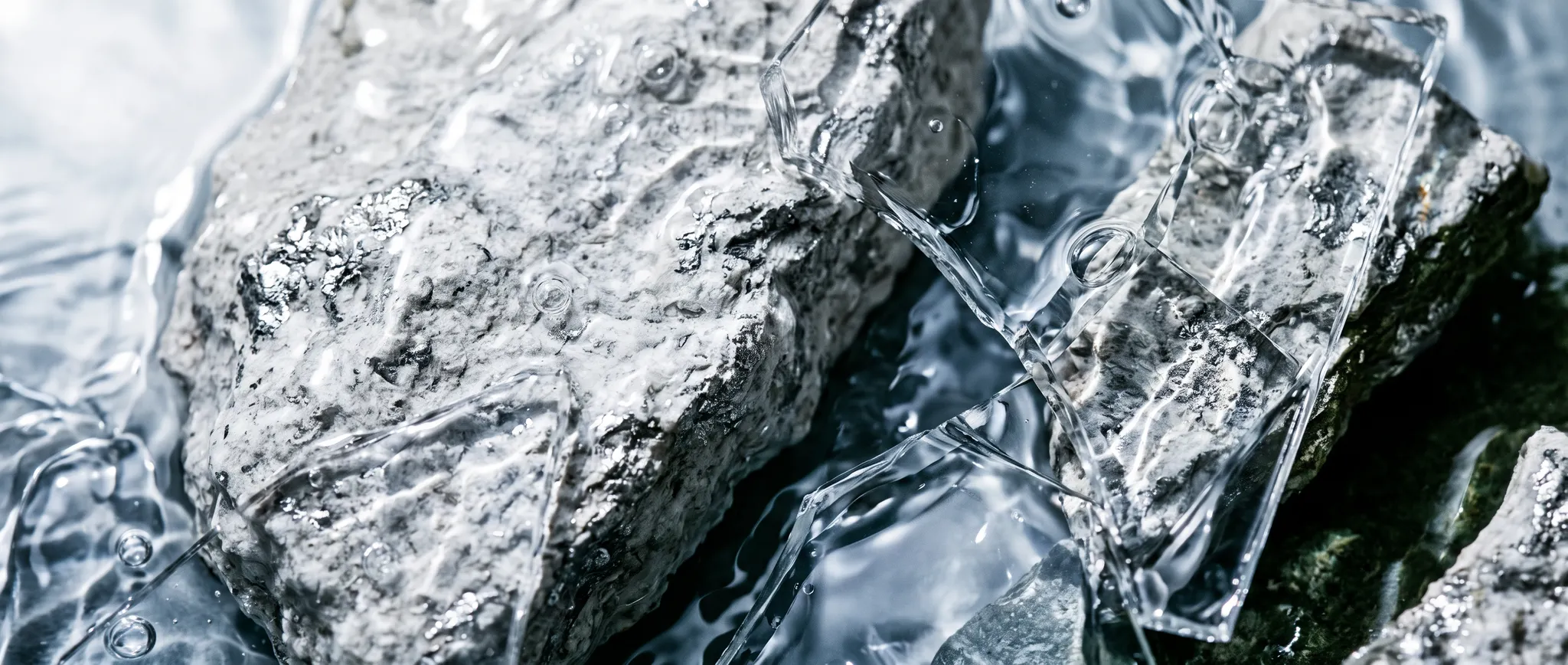 Clear water moving across silver mineral stone and glass
