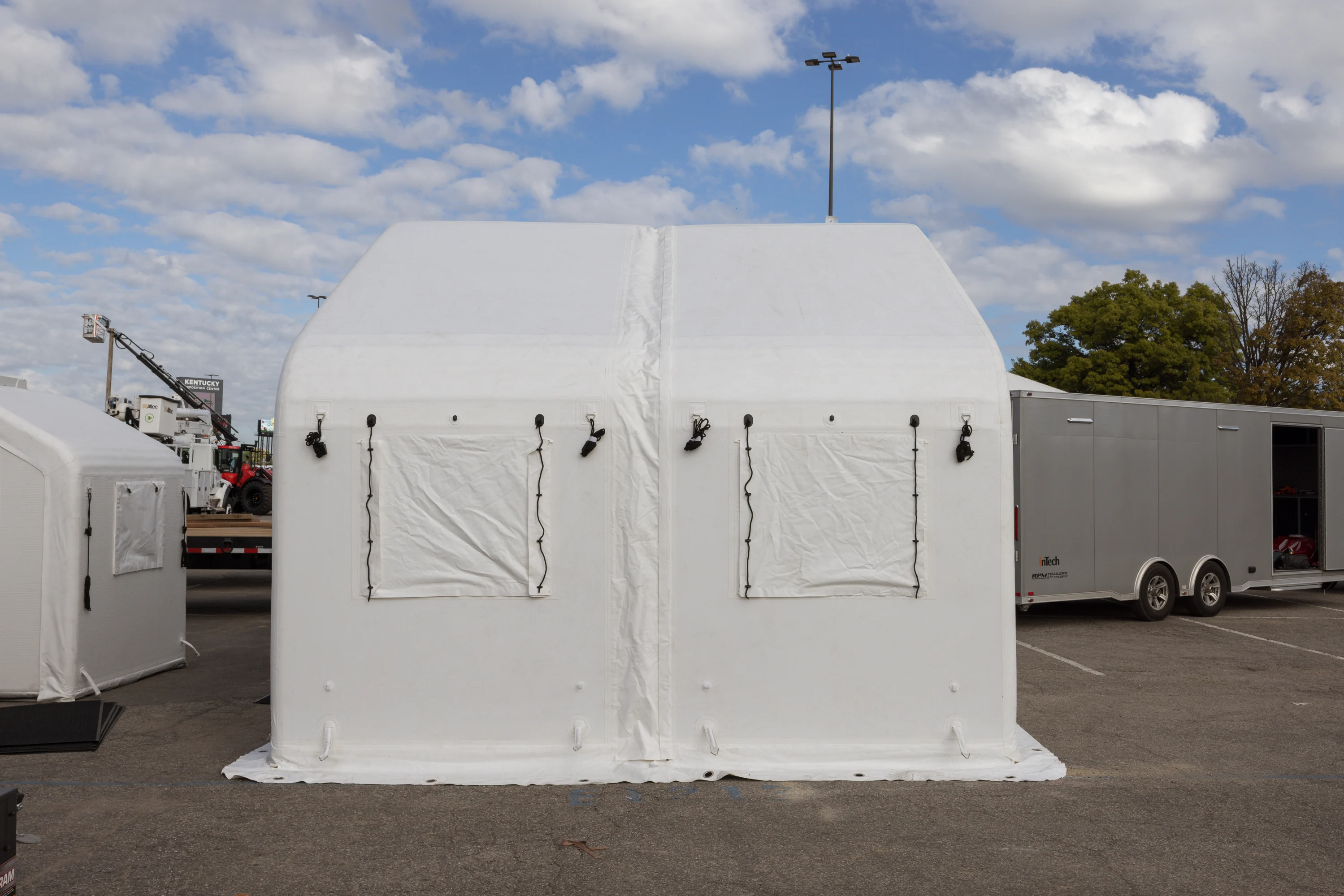 Side of a white drop-stitch inflatable tent with covered windows and visible panel connections
