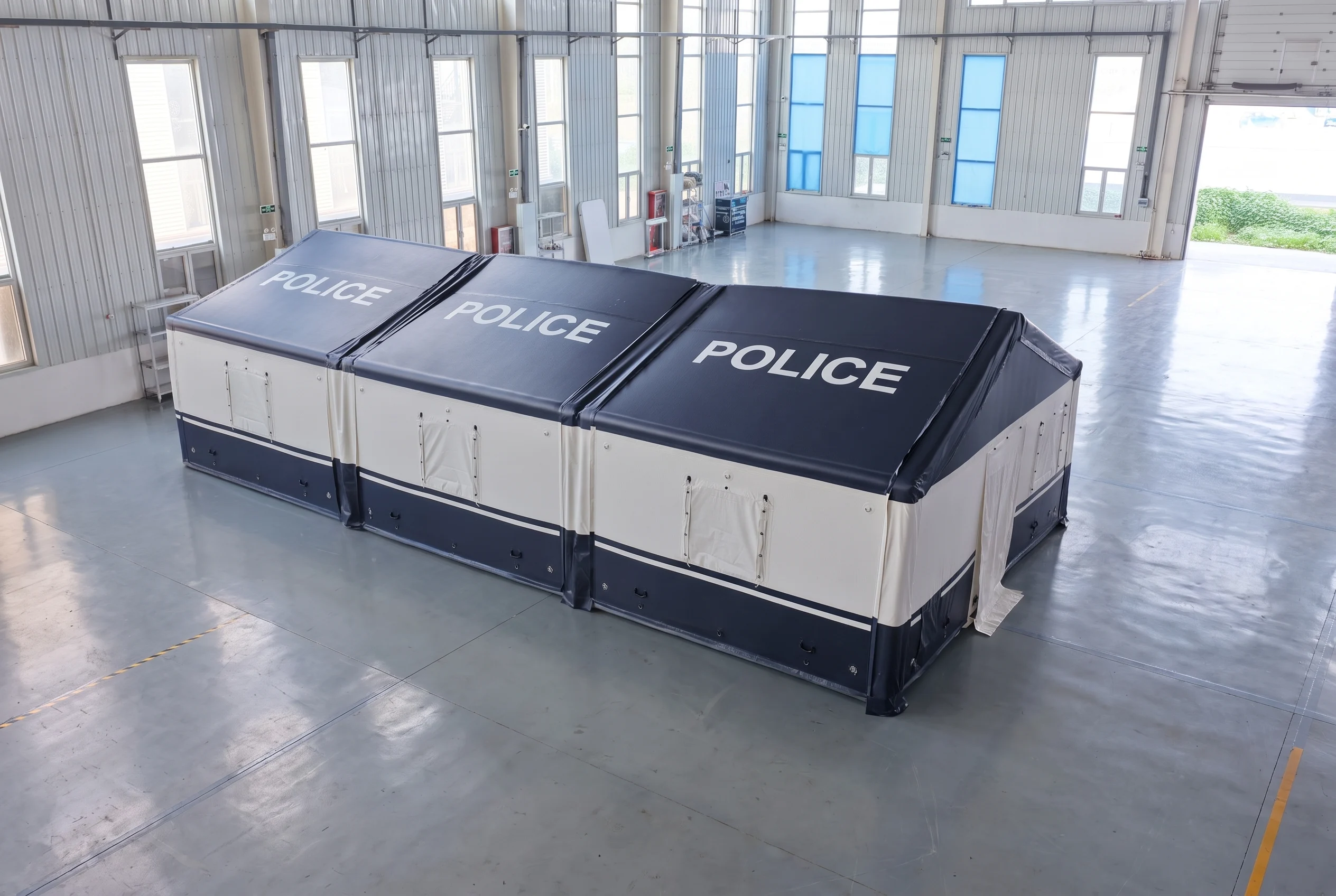Three navy and white drop-stitch inflatable tent modules joined end-to-end inside a building
