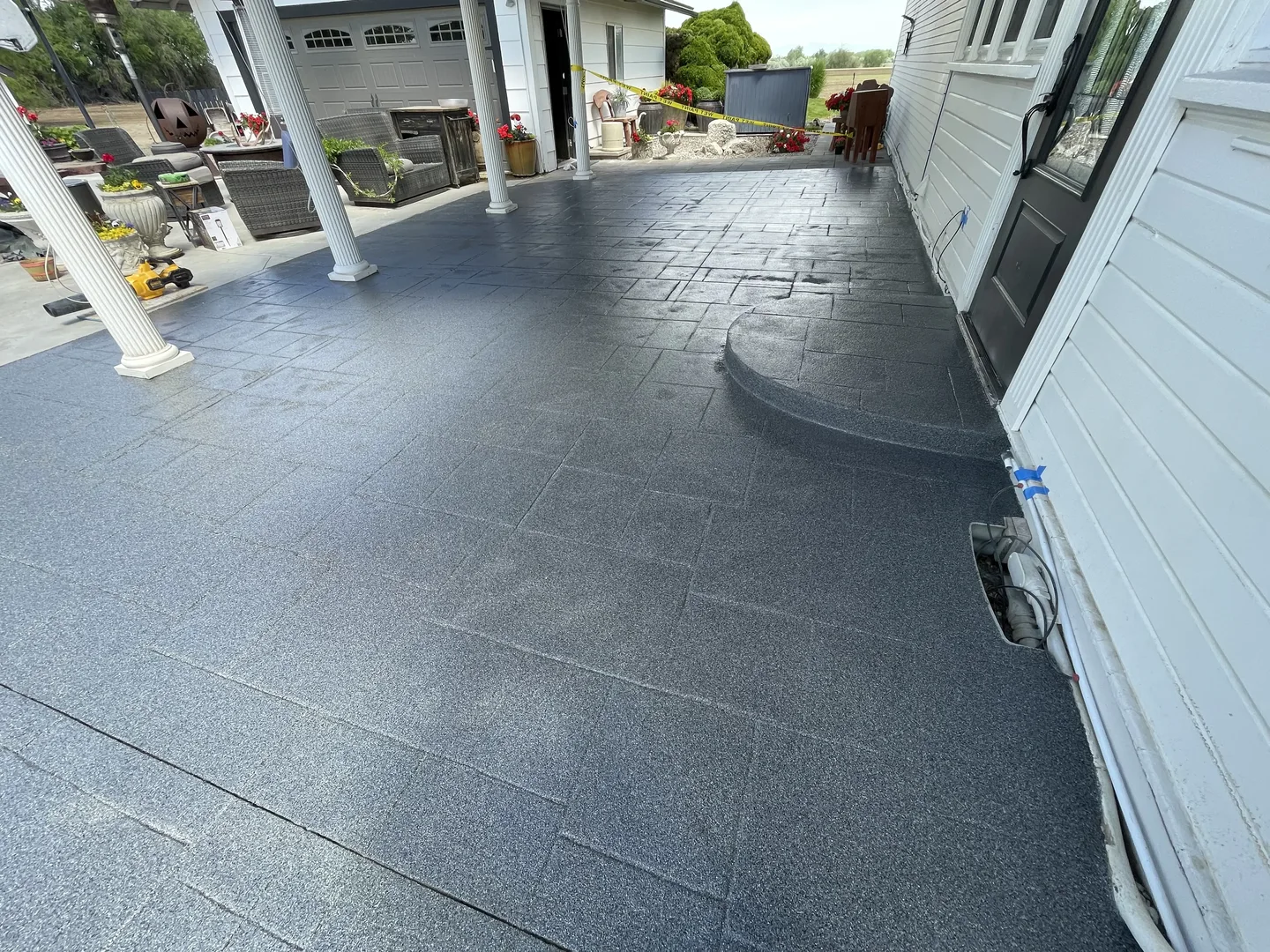 Gray patterned concrete overlay on a covered patio by Yankee Coatings
