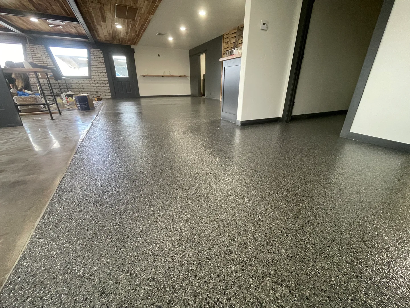 Gray flake epoxy floor in an interior space with brick walls and a wood ceiling