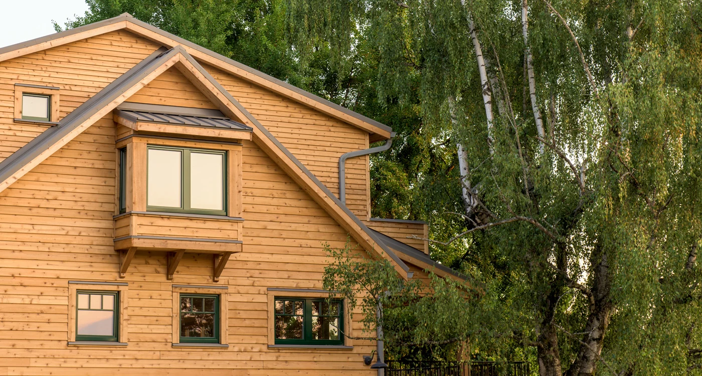 Wood-clad high-performance home beneath tall trees, designed and built by Birdsmouth Design-Build